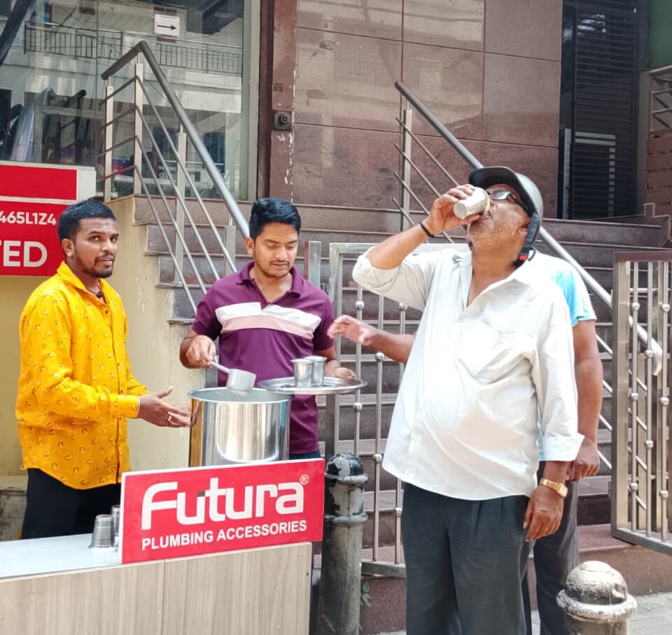 People enjoying free buttermilk served by Futura Kitchen Sinks and Plumbing Accessories during a summer CSR drive outside the company headquarters in Bengaluru.